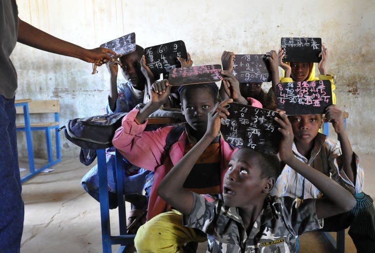 A teacher checks students' chalk boards in a classroom in Gao on February 4, 2013. In Gao, French-led forces have beefed up security to prevent rebels infiltrating the city, according to a Malian army source, while an AFP journalist reported large patrols by French, Malian and Nigerien troops