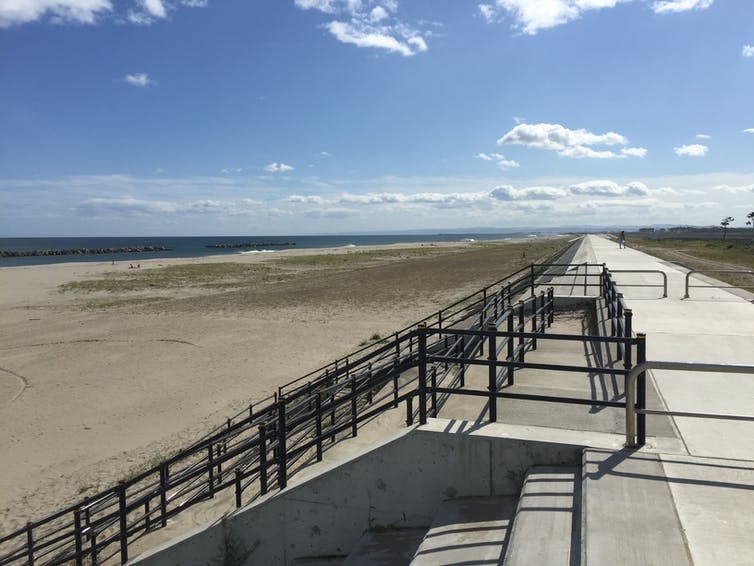 A coastal concrete wall covered in metal railings.