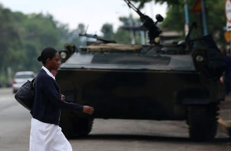 A woman walks past an armoured vehicle in Harare, Zimbabwe, November 18, 2017. REUTERS/Philimon Bulawayo