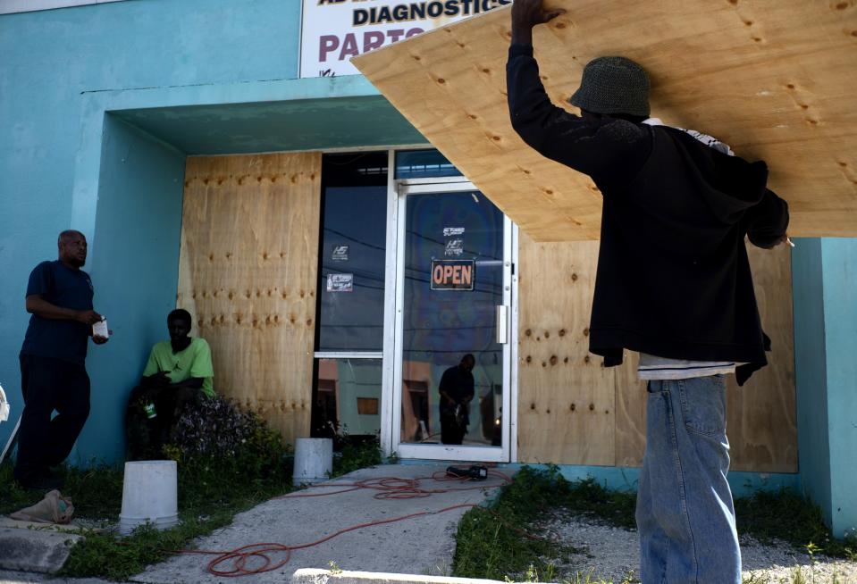 Workers board up a shop’s window front as they make preparations for the arrival of Hurricane Dorian, in Freeport, Bahamas, Friday, Aug. 30, 2019. Forecasters said the hurricane is expected to keep on strengthening and become a Category 3 later in the day. (AP Photo/Ramon Espinosa)