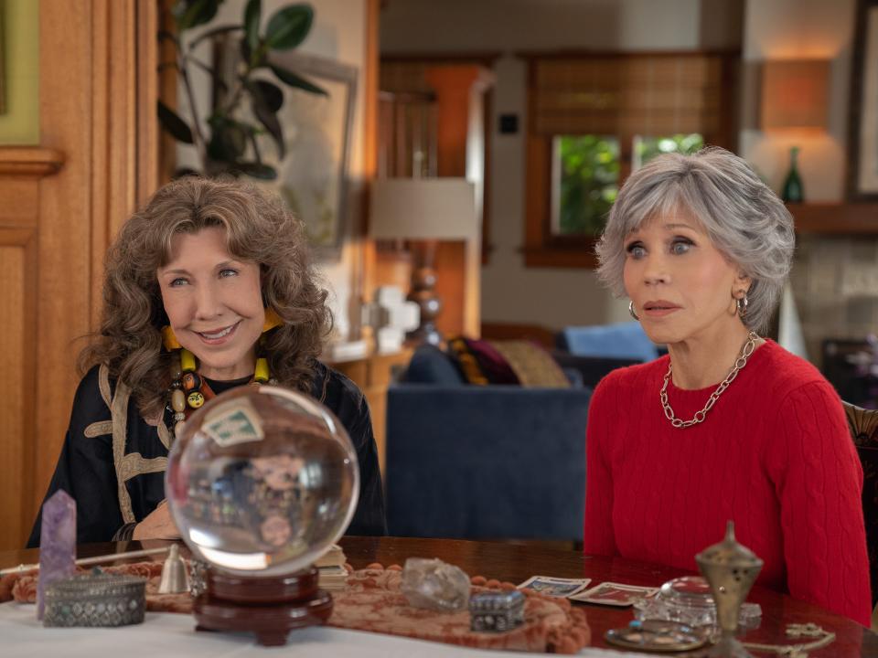 Lily Tomlin and Jane Fonda sitting at table with crystal ball in "Grace and Frankie"