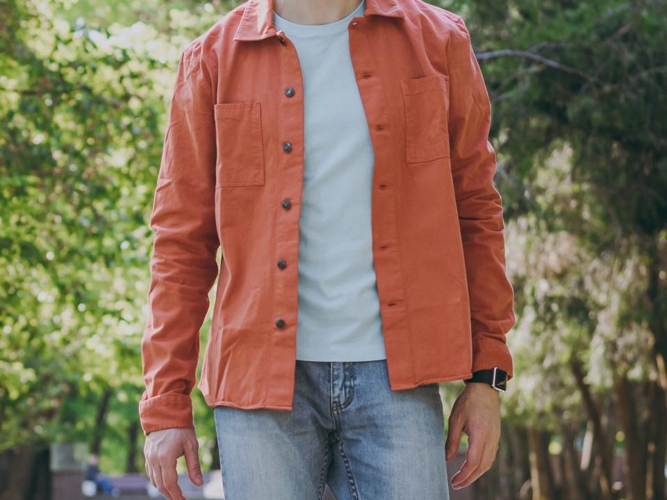 Man wearing jeans, t-shirt, and orange shirt.