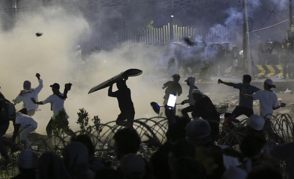 Supporters of the losing presidential candidate throw rocks towards police Wednesday, May 22, 2019, in Jakarta, Indonesia. Indonesian President Joko Widodo said authorities have the volatile situation in the country's capital under control after a number of people died Wednesday in riots by supporters of his losing rival in last month's presidential election. (AP Photo/Achmad Ibrahim)