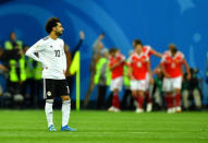 Soccer Football - World Cup - Group A - Russia vs Egypt - Saint Petersburg Stadium, Saint Petersburg, Russia - June 19, 2018 Egypt's Mohamed Salah looks dejected while Russia's Artem Dzyuba celebrates scoring their third goal with team mates REUTERS/Dylan Martinez