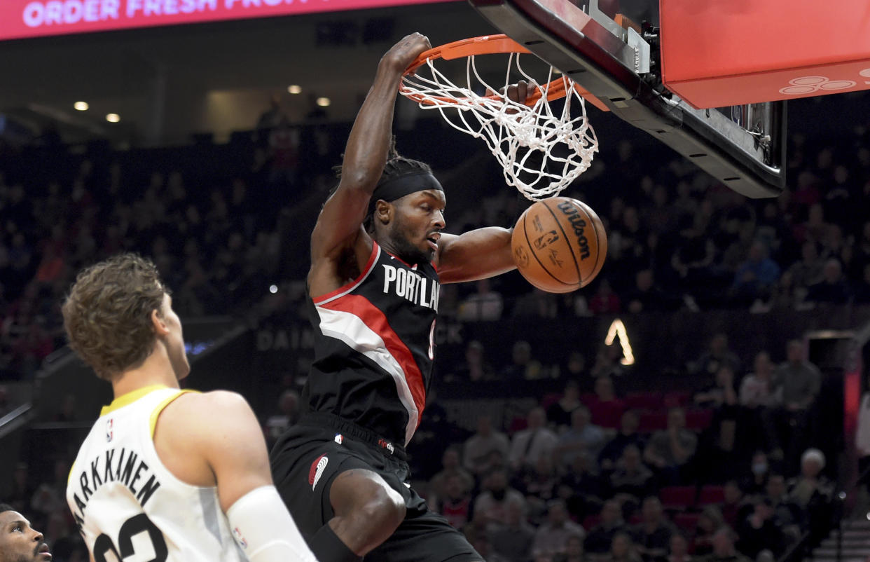 Trail Blazers forward Jerami Grant, right, dunks near Jazz forward Lauri Markkanen, left, during the first half of their game Wednesday in Portland. (AP Photo/Steve Dykes)