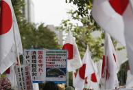 A member of the nationalist movement "Ganbare Nippon" holding a placard of disputed islands known as Senkaku in Japan and Diaoyu in China, walks among Japanese national flags during a rally in Tokyo September 11, 2013, on the day of one year anniversary of Japanese government signed contract to buy islands disputed with China from a private owner. China said it would not tolerate provocation after Japan's top government spokesman said on Tuesday Japan might station government workers on disputed islands in the East China Sea to defend its sovereignty. Relations between the world's second- and third-biggest economies have been strained over the uninhabited isles which Japan controls but both countries claim. Placard reads, "No TPP (Tran-Pacific Partnership), No sales Tax hike, Protect our national interest, Senkaku islands are Japanese territories, Don't permit Chinese territorial waters violation." (REUTERS/Toru Hanai)