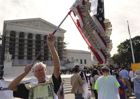 David Barrows (L) waves a self-made U.S. flag covered in fake currency and corporate logos during a protest in front of the U.S. Supreme Court in Washington October 8, 2013. REUTERS/Gary Cameron