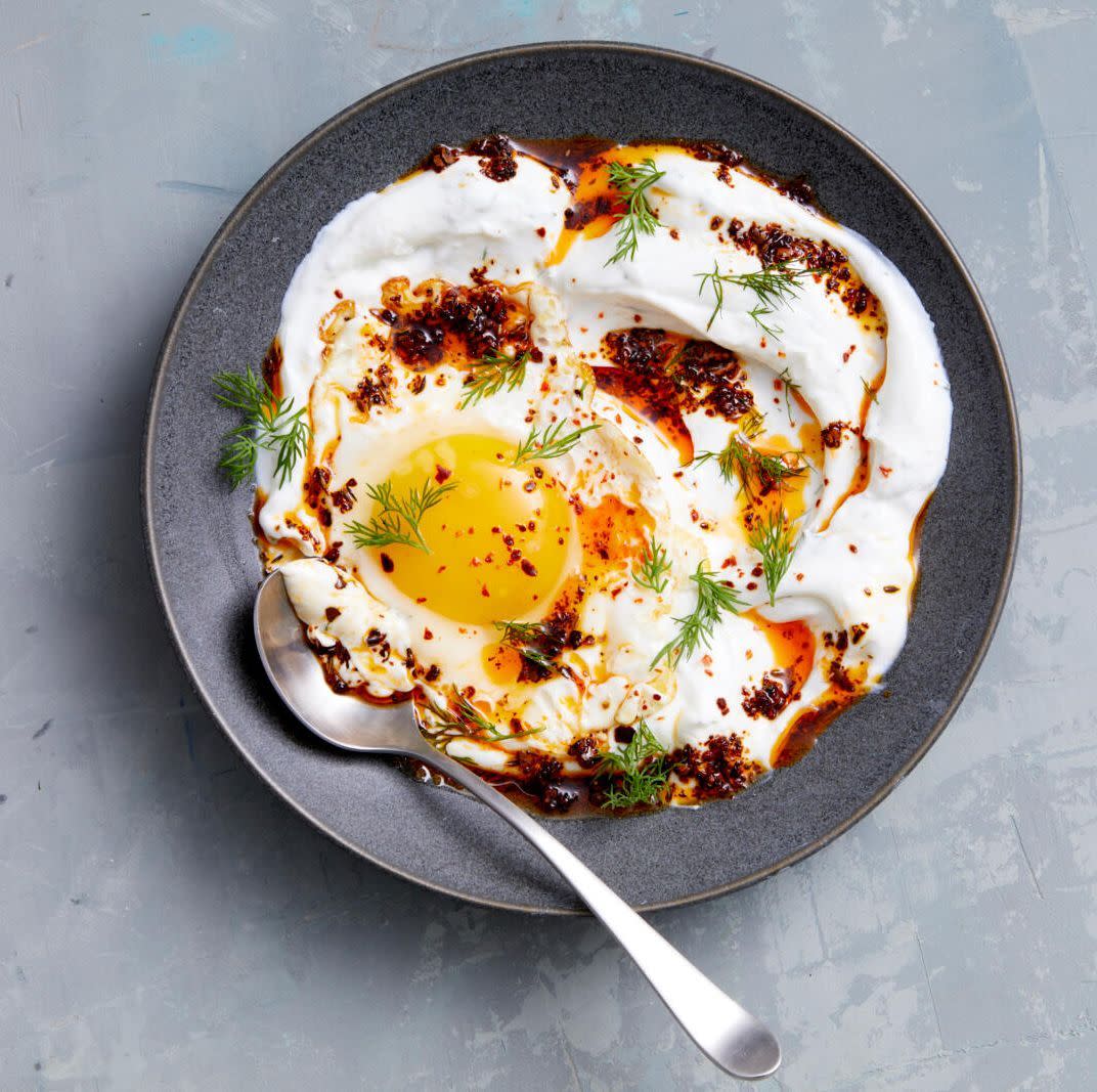 turkish eggs with yogurt in a dark gray bowl on a light gray background