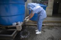 Davisela Abril se lava las manos tras darle de comer y bañar a su padre en la unidad de COVID-19 del Hospital José Gregorio Hernández de Caracas el 4 de octubre del 2020. (AP Photo/Ariana Cubillos)