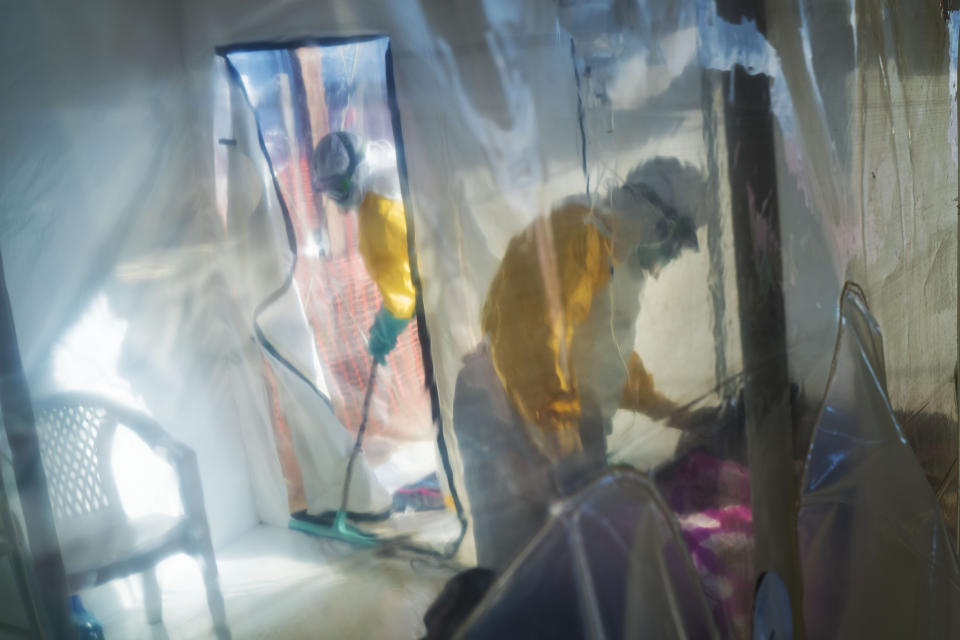 In this photograph taken Saturday 13 July 2019, health workers wearing protective suits tend to to an Ebola victim kept in an isolation cube in Beni, Congo DRC. The Congolese health ministry is confirming the country's first Ebola case in the provincial capital of 2 million, Goma, some 360 kms ( 225 miles) south of Beni. More than 1,600 people in eastern Congo have died as the virus has spread in areas too dangerous for health teams to access. (AP Photo/Jerome Delay)