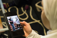 Faeza Satouf looks at a photo of her graduation day on her phone during an interview in Nivaa, Denmark, Wednesday, April 21, 2021. The 25-year-old Syrian refugee had fled the civil war with her family in an all-too-familiar journey across the sea to Europe, where they finally arrived in Denmark and were granted asylum in 2015. Yet six later years, she has been told she has to go back — alone, and soon. (AP Photo/David Keyton)