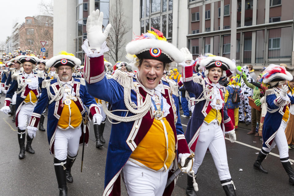 Mainz, Germany - March 3, 2014: Colourful costumed participants of Rose Monday parade in the city center of Mainz - waving and cheering. Spectators in the background. Rosenmontagszug in Mainz is one of the largest and most famous carnival parades in Germany with approx. 500.000 spectators