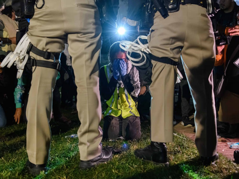 A pro-Palestinian protester kneels in front of two California Highway Patrol officers in Los Angeles on May 1.<span class="copyright">Jeremy Chen for The Daily Bruin</span>