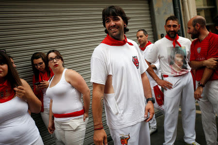 A woman looks at Sergio Colas as he meets with other runners after a crowded bull run at the San Fermin festival in Pamplona, northern Spain, July 10, 2016. His shirt got caught in the horn of a steer during the run and he ripped it to get loose while running. REUTERS/Susana Vera