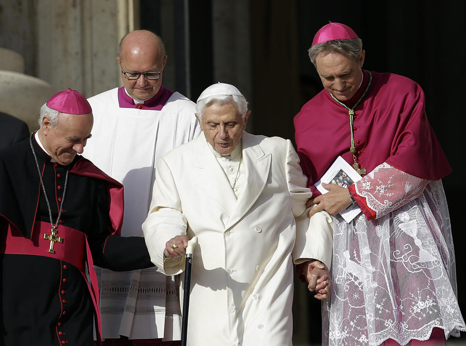 FILE - Pope Emeritus Benedict XVI, center, is helped to walk down the steps by Bishops Vincenzo Paglia, left, and Georg Gaenswein prior to the start of a meeting of Pope Francis with the elderly in St. Peter's Square at the Vatican, on Sept. 28, 2014. Pope Francis has exposed the political “maneuvers” to sway votes during the past two conclaves and denied he is planning to reform the process to elect a pope in a new book-length interview published Tuesday April 2, 2024. (AP Photo/Gregorio Borgia, File)