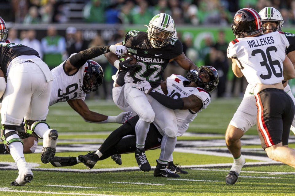 Marshall's Rasheen Ali (22) fights his way upfield on a carry against Arkansas State's Thurman Geathers (92) and James Reed (19) during an NCAA college football game Saturday, Nov. 25, 2023, in Huntington, W.Va. (Sholten Singer/The Herald-Dispatch via AP)