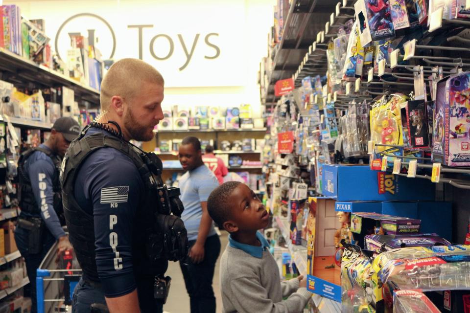 West Palm Beach Police Officer Josh Hall and 7-year-old Donel Pierre Jr. browse Walmart's toy selection on Dec. 7, 2022.