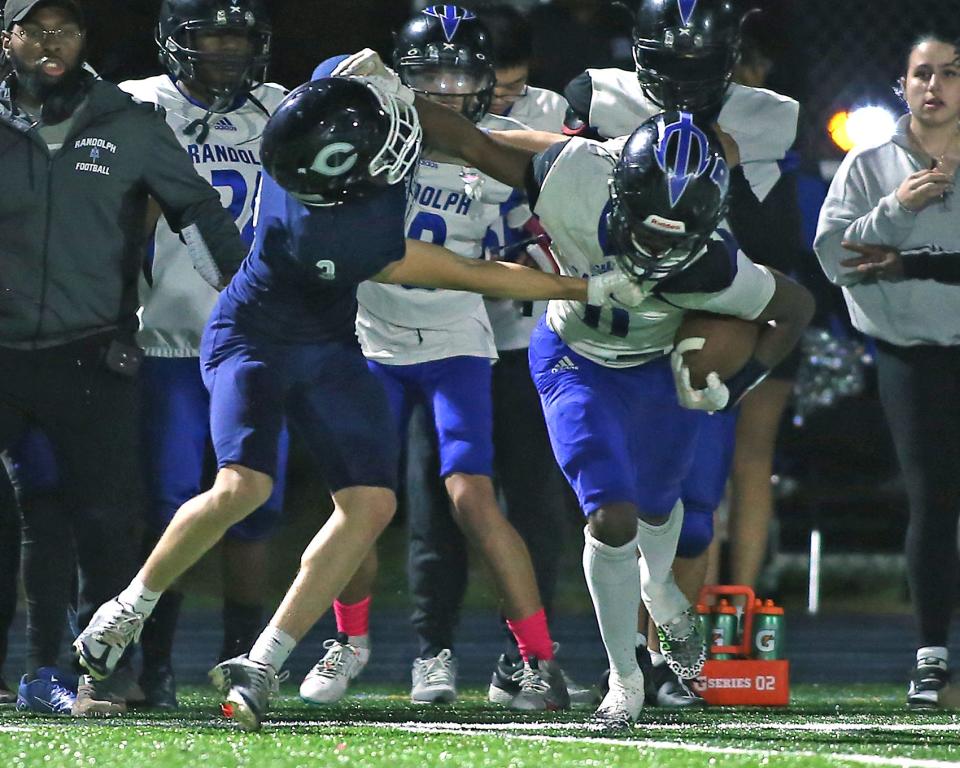 Randolph's Nathanyel Gomes Correia tries to stiff arm Cohasset's Jack Harries during third quarter action of their game at Cohasset Middle High School on Friday, Oct. 27, 2023. Cohasset would go on to win 43-6.