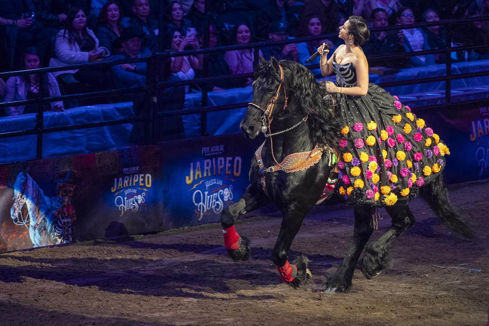 Mexican and American singer Angela Aguilar, the daughter of Grammy-winning singer songwriter Pepe Aguilar, rides her horse s she sings at the "Jaripeo Hasta Los Huesos Tour 2024" show at the Honda Center in Anaheim, Calif., on Friday, March 29, 2024. The show pays tribute to the Day of the Dead, a well-known Mexican celebration. (AP Photo/Damian Dovarganes)