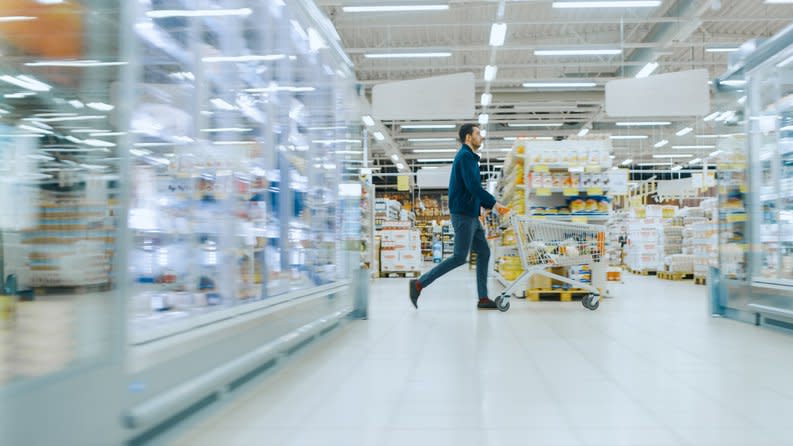 A man pushes a shopping cart through the aisles of a department store.