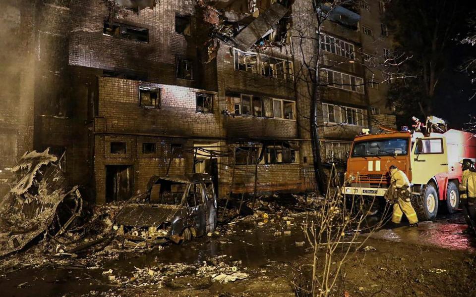 Russian firefighters extinguishing the fire in the residential building at the crash site in Yeysk - Shutterstock