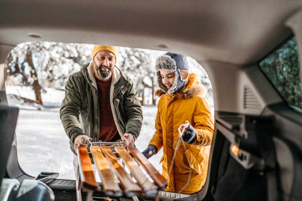 Father and son taking a toboggan out of the trunk to go sledding