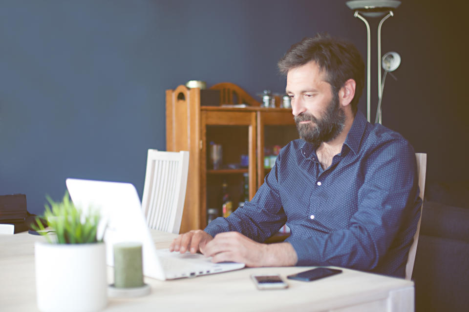 focused middle aged entrepreneur sitting at the desk,working from home, casual businessman using laptop computer working and communication with customer for order purchasing and delivering information in modern home office, online shopping business concept