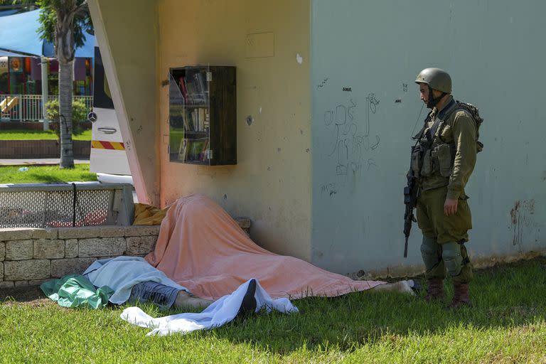 Un soldado israelí junto a los cuerpos de israelíes asesinados por militantes armados palestinos que ingresaron desde la Franja de Gaza, en la ciudad de Sderot, en el sur de Israel