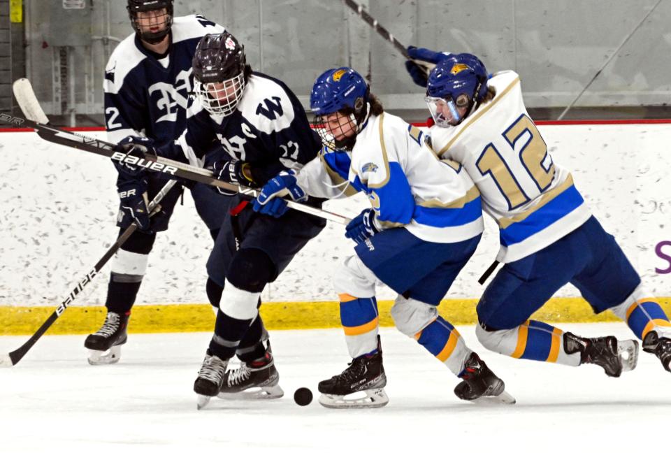 Jack Billings of Nantucket and Sean Willis and Jamie Erikson (12) of John Paul II attempt to control the puck during a Feb. 23rd game.