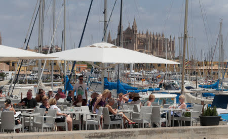 Tourists enjoy sun in a terrace at Palma de Mallorca's port, in the Spanish island of Mallorca, May 23, 2016. REUTERS/Enrique Calvo