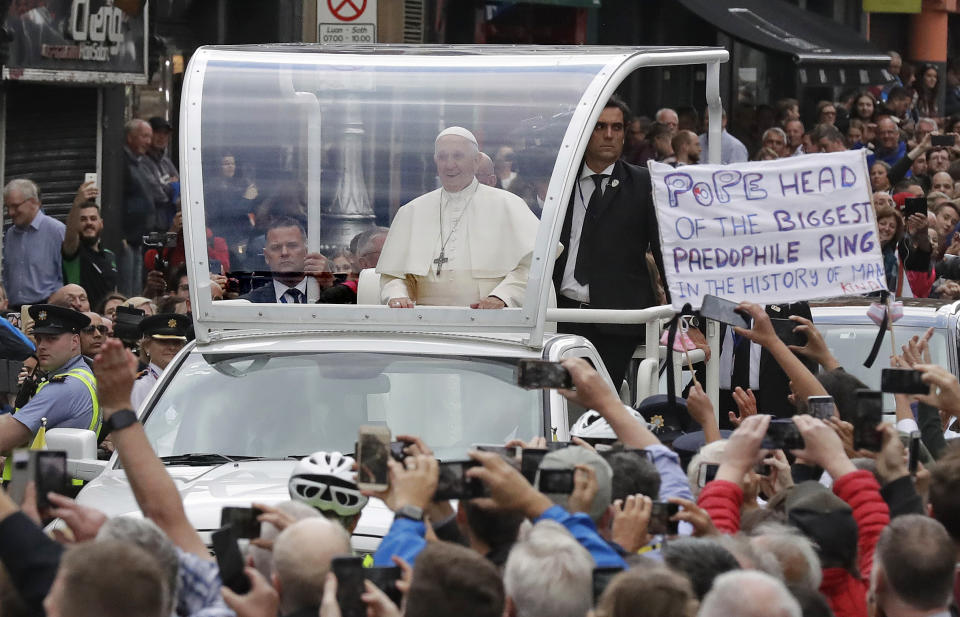 Pope Francis passes by a banner of a protester as he leaves after visiting St Mary's Pro-Cathedral, in Dublin, Ireland, Saturday, Aug. 25, 2018. Pope Francis is on a two-day visit to Ireland. (AP Photo/Matt Dunham)