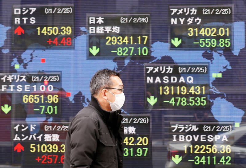 FILE PHOTO: A man walks past a stock quotation board at a brokerage in Tokyo, Japan