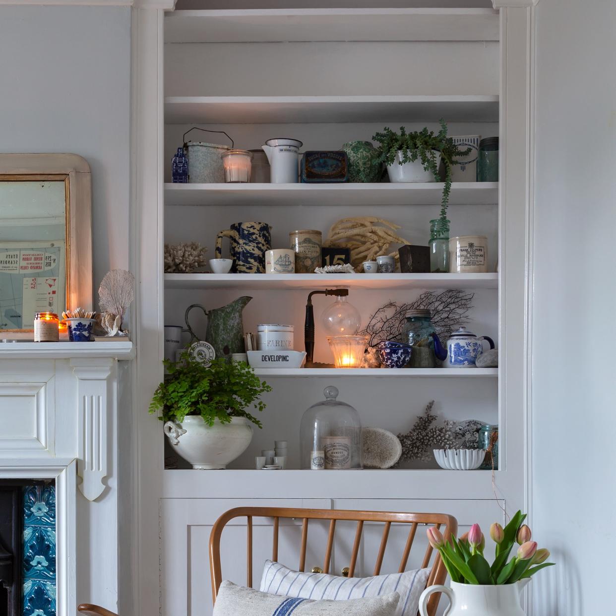  Built-in living room shelves displaying lit scented candles and other decorative objects. 