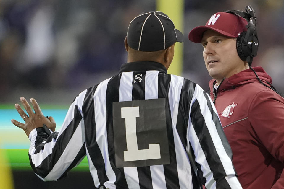 Washington State acting head coach Jake Dickert, right, talks to an official during the second half of an NCAA college football game against Washington, Friday, Nov. 26, 2021, in Seattle. (AP Photo/Ted S. Warren)