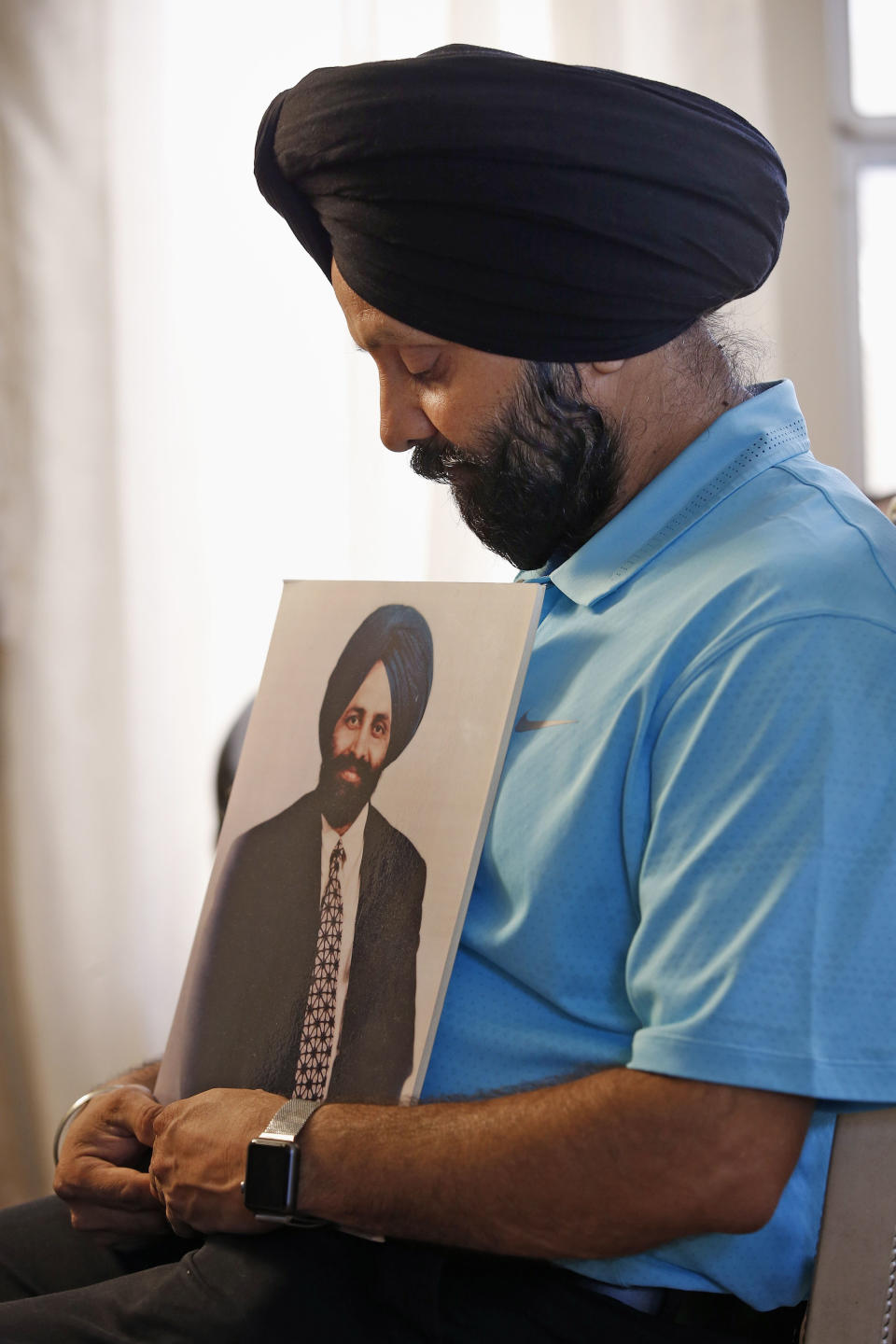 FILE - In this Aug. 19, 2016 file photo Rana Singh Sodhi, holds a photograph of his murdered brother, Balbir Singh Sodhi, in Gilbert, Ariz. The Sikh American was killed at his Arizona gas station four days following the Sept. 11 attacks by a man who announced he was "going to go out and shoot some towel-heads" and mistook him for an Arab Muslim. (AP Photo/Ross D. Franklin,File)