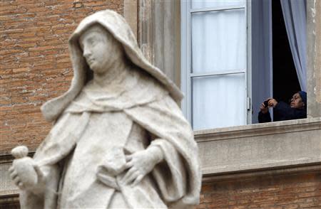 A nun takes a picture from a window in St Peter's Square where Pope Francis is conducting a mass to prepare an urn containing the relics of the Apostle St. Peter for public veneration, at the Vatican November 24, 2013. REUTERS/Stefano Rellandini