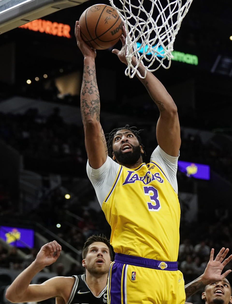 Los Angeles Lakers' Anthony Davis (3) dunks as San Antonio Spurs' Doug McDermott, left, and Dejounte Murray look on during the first half of an NBA basketball game on Tuesday, Oct. 26, 2021, in San Antonio, Texas. (AP Photo/Darren Abate)