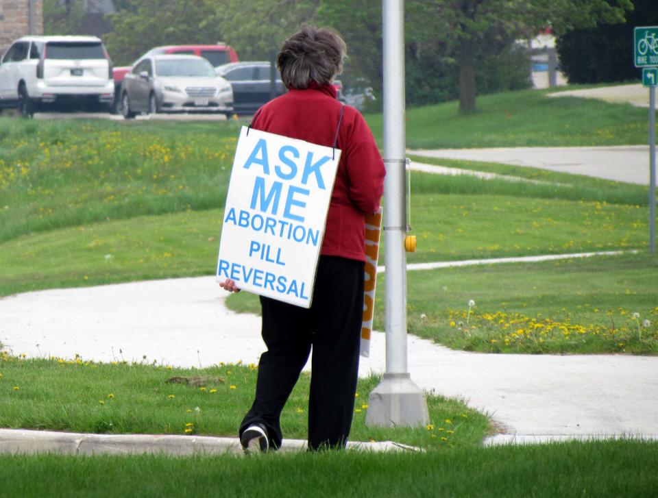 A woman walks with a sandwich board near Planned Parenthood, Thursday, May 19, 2022, in Sheboygan, Wis.