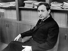 Black and white image of a man sitting down.