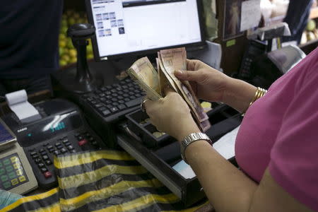 A cashier counts Venezuelan bolivar notes at a fruit and vegetable store in Caracas July 10, 2015. REUTERS/Marco Bello