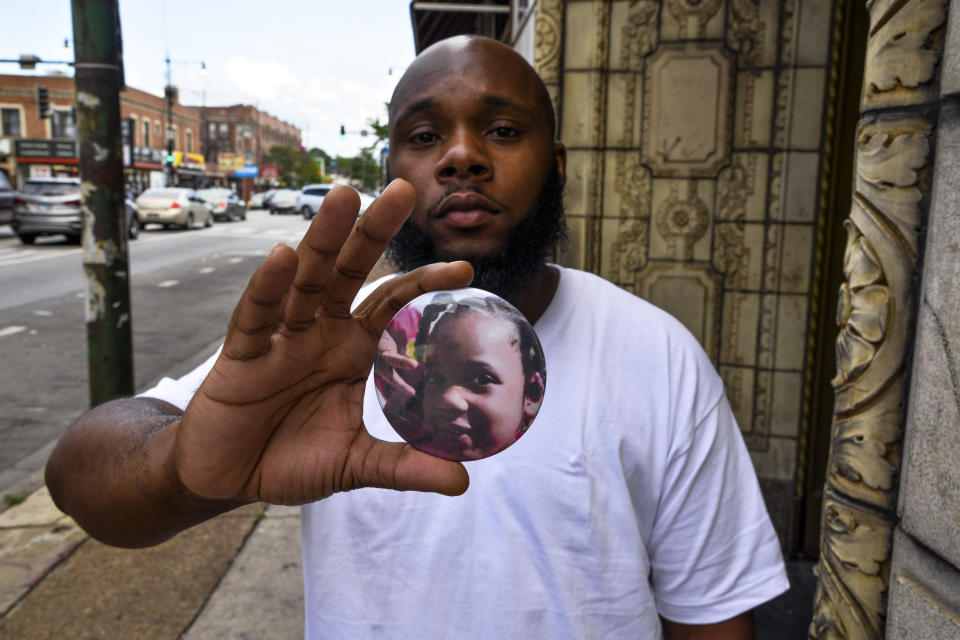 Nathan Wallace stands outside of his home holding a button showing his daughter, Natalia Wallace, on Monday, Aug. 3, 2020, in Chicago. Natalia, 7, was killed on the west side of Chicago on July 4, 2020. (AP Photo/Matt Marton)