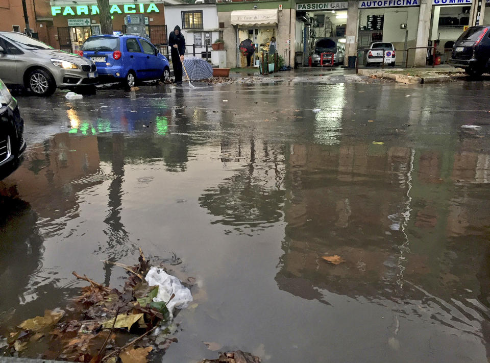 A manhole is clogged by leaves and plastic causing a giant puddle partially flooding a street as a man on the other side of the road tries to sweep away more leaves, in Rome, Monday, Nov. 5, 2018. Rome’s monumental problems of garbage and decay exist side-by-side with Eternal City’s glories. (AP Photo/Alessandra Tarantino)