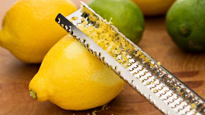 Lemon being zested with a metal peeler