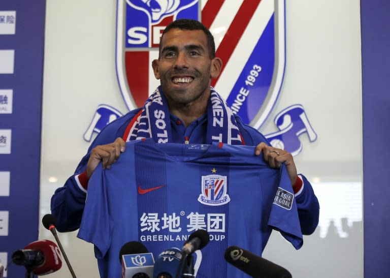 This file photo taken on January 21, 2017 shows Argentine striker Carlos Tevez posing with a jersey of his new club Shanghai Shenhua during a press conference in Shanghai on January 21, 2017. The Chinese Super League will take another step towards global recognition when it returns on March 3, 2017, boasting the world's richest players and a growing audience including live broadcasts in Britain. When Argentina's Carlos Tevez makes his league debut for Shanghai Shenhua, fans from Liaoning to Liverpool can tune in to see what can be bought with reported wages of 768,000 USD a week