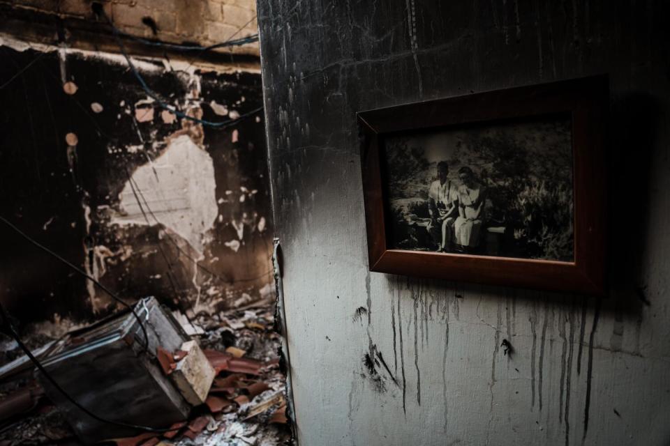 A family photo hangs on the wall of a burned-out house