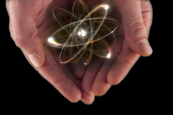 Cupped hands holding an image of an atom