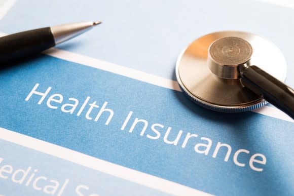 Health insurance document with a pen and a stethoscope on top