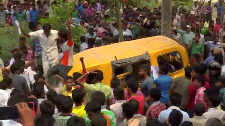 People gather around a school bus after it collided with a train in Uttar Pradesh, India April 26, 2018, in this screen grab taken from video. ANI via REUTERS