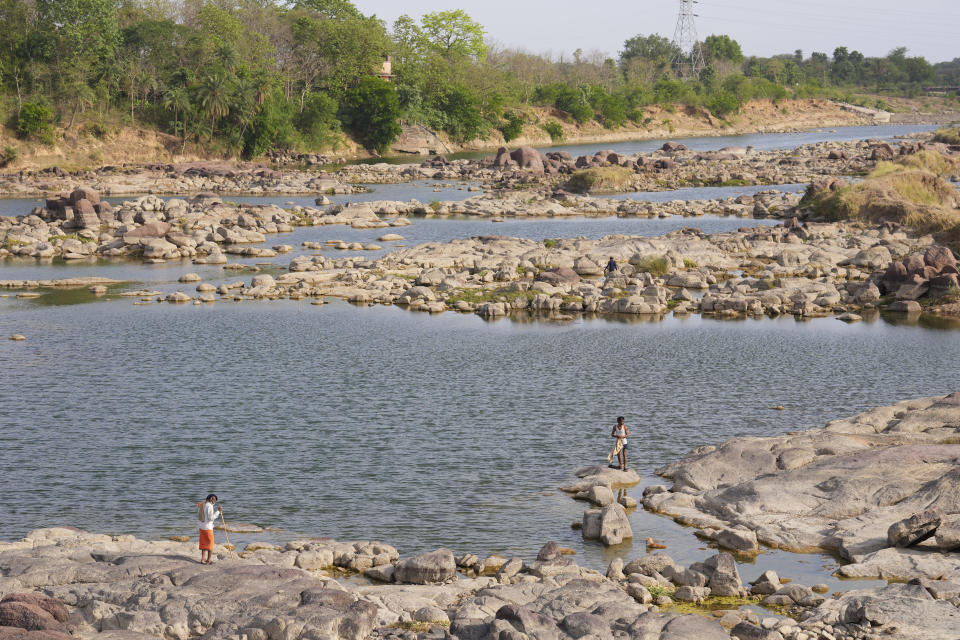 People stand on the rocks at the River Dhasaan whose water level has fallen in Ghuwara, Chhatarpur District, Madhya Pradesh state, India, Sunday, June 18, 2023. Swaths of two of India's most populous states are under a grip of sever heat leaving dozens of people dead in several days as authorities issue a warning to residents over 60 and others with ailments to stay indoors during the daytime. (AP Photo/Rajesh Kumar Singh)