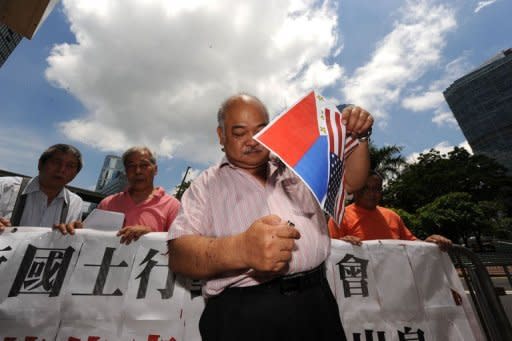 A Hong Kong protester who supports Chinese sovereignty over the Scarborough Shoal, burns Philippine and US flags